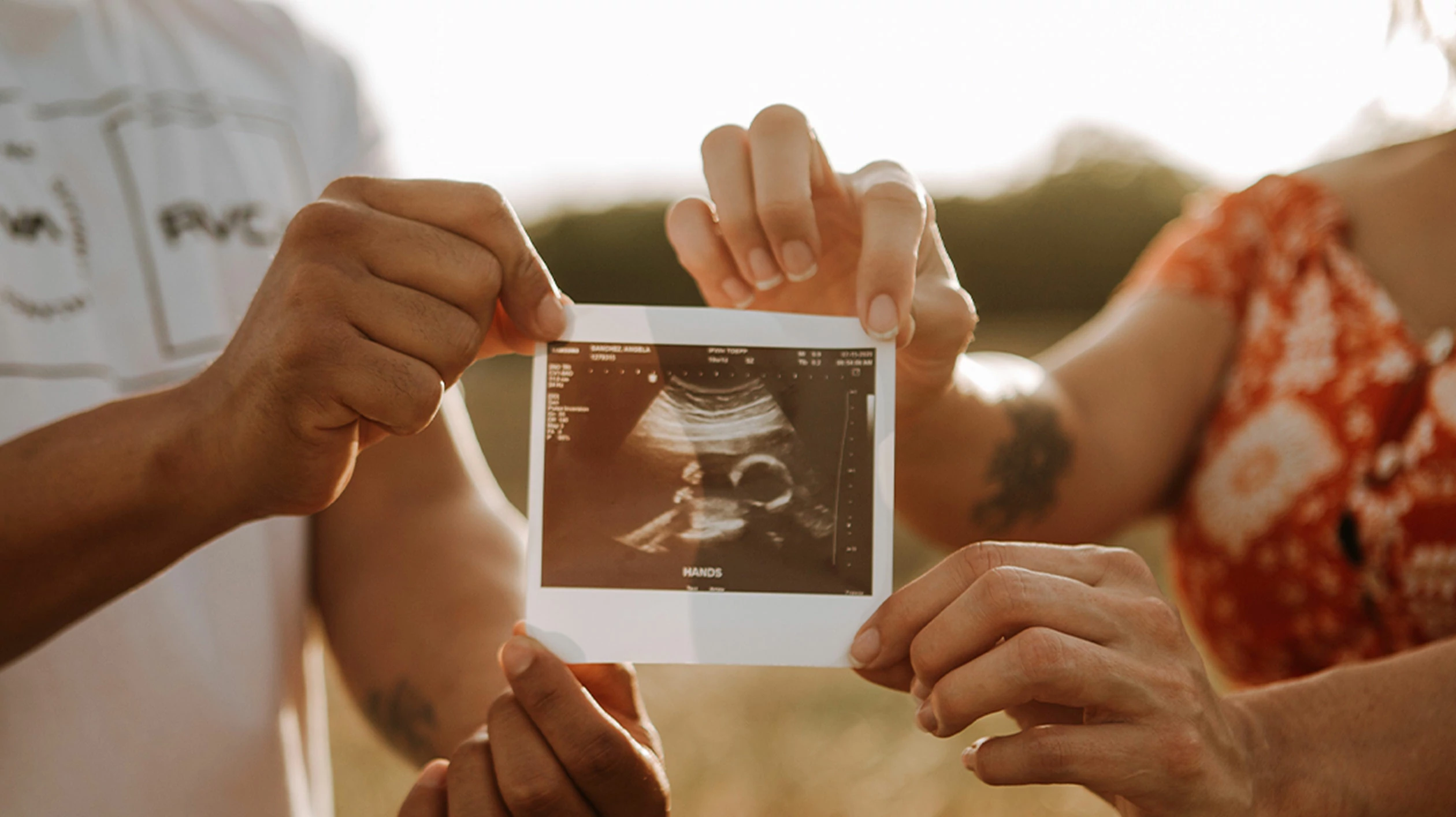 A woman and a man hold the ultrasound image of an embryo