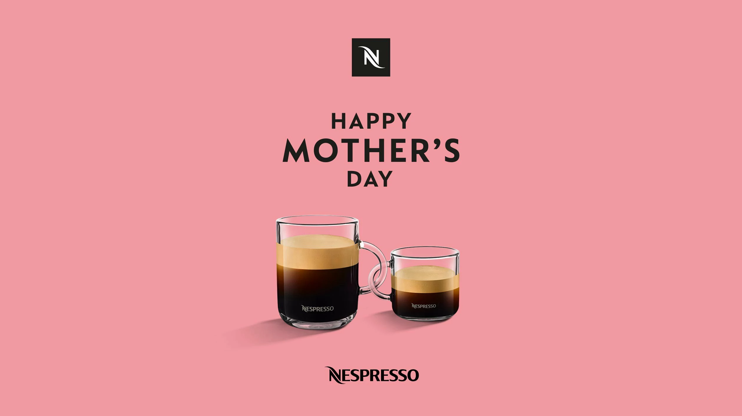 Zwei Nespresso Kaffeetassen vor einem einfarbigen Hintergrund. Die Henkel der Tassen sind ineinander verschlungen. Über den Tassen steht “Happy Mother‘s Day”.