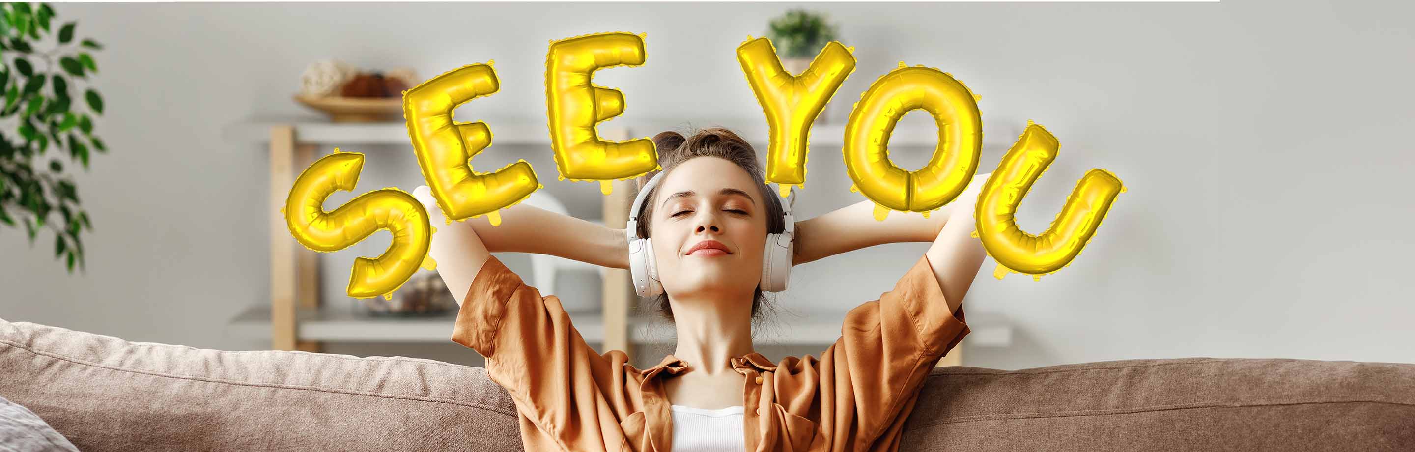 A relaxed young woman with her hands behind her head and headphones on a sofa. Around her head is the lettering "See you" in the form of golden balloons.