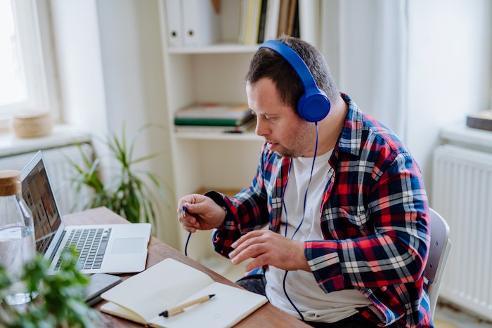 Ein Mann mit Down-Syndrom am Computer, der einen Kopfhörer trägt